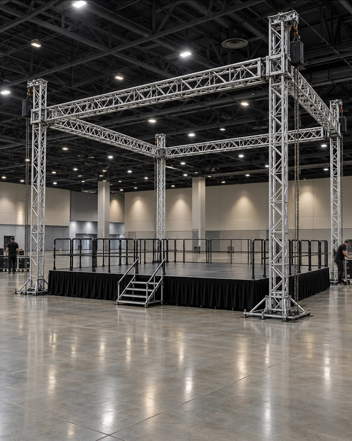 Box truss grid on four ground support towers over a modular stage in a convention hall
